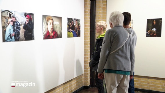 Menschen betrachten die Ausstellung der UNICEF-Siegerfotos. © Screenshot 