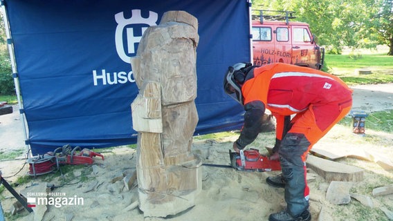 Ein Mann fertigt mit einer Kettensäge eine Holzskulptur. © Screenshot 