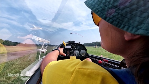 Eine Frau sitzt im Cockpit eines Segelflugzeuges und startet zum Flug. © Screenshot 