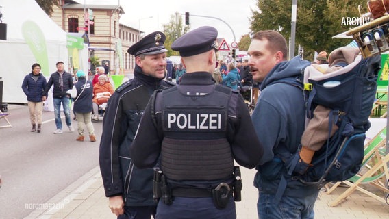 Zwei Polizisten im Gespräch mit einem Mann. © Screenshot 