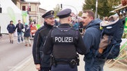 Zwei Polizisten im Gespräch mit einem Mann. © Screenshot 