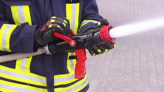 Jemand in Feuerwehruniform hält einen Wasserschlauch © Screenshot 