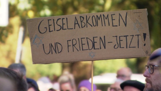 Ein Schild mit der Aufschrift: "Geiselabkommen und Frieden - Jetzt". © Screenshot 