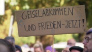 Ein Schild mit der Aufschrift: "Geiselabkommen und Frieden - Jetzt". © Screenshot 