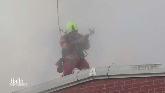 Ein Feuerwehrmann steht im dichten Rauch auf dem Dach eines Gebäudes. © Screenshot 