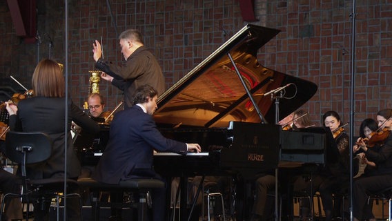 Der Pianist Rafał Blechacz spielt auf einer Bühne mit der NDR Elbphilharmonie. © Screenshot 