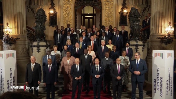 Olaf Scholz und weitere internationale Staats- und Regierungschefs stehen auf einer Treppe. © Screenshot 