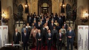 Olaf Scholz und weitere internationale Staats- und Regierungschefs stehen auf einer Treppe. © Screenshot 