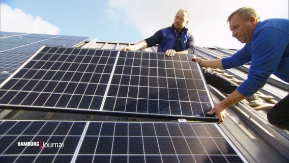 Zwei Männer montieren eine Solarzelle auf einem Dach. © Screenshot 