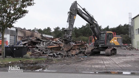 Ein Bagger räumt verkohlte Trümmer weg. © Screenshot 