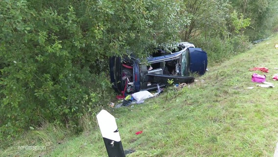 Ein ramponiertes Auto liegt am Fuße einer Böschung auf der Seite. © Screenshot 