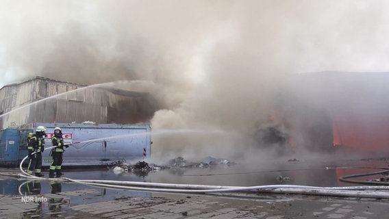 Feuerwehrleute löschen einen Brand auf dem Gelände einer Müllentsorgungsfirma. © Screenshot 