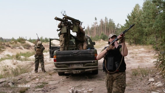 Ukrainische Frauen mit Gewehr im Anschlag und auf einem Militärfahrzeug. © Screenshot 