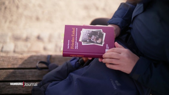 Eine Frau hält ein Buch in den Händen. © Screenshot 