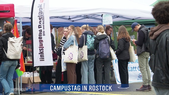 Junge Menschen informieren sich an einem Stand am Campustag der Universität Rostock. © Screenshot 