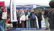 Junge Menschen informieren sich an einem Stand am Campustag der Universität Rostock. © Screenshot 