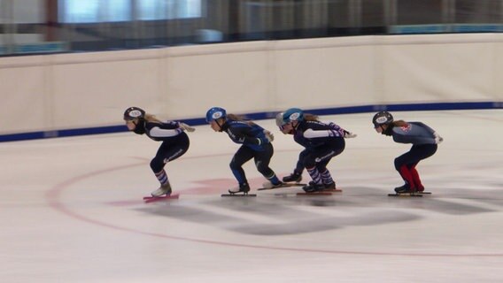 Mehrere Sportler laufen bei einem Short Track Wettkampf auf dem Eis. © Screenshot 