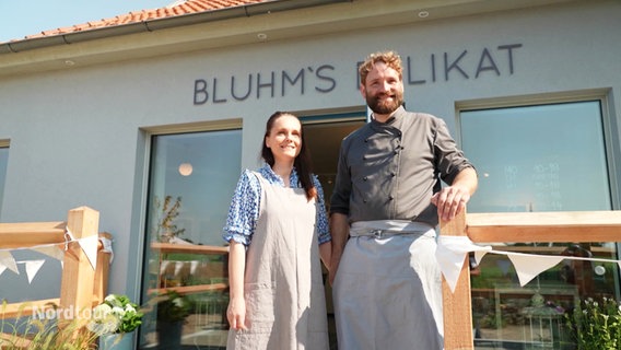 Robert Bluhm und Sophie Junghans stehen lächelnd vor "Bluhms Delikat". © Screenshot 