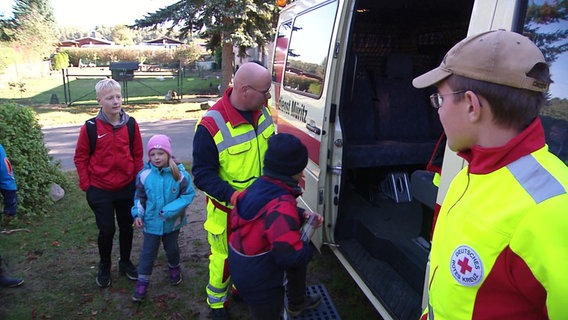 Einsatzkräfte helfen Kindern in einen Rettungswagen. © Screenshot 