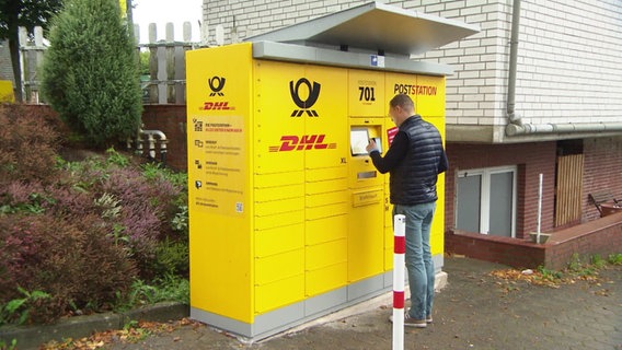 Ein mann steht an einer Packstation und tippt auf den Bildschirm. © Screenshot 