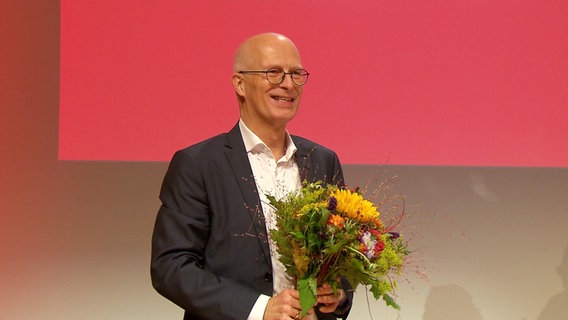 Peter Tschentscher hält einen Blumenstrauß. © Screenshot 