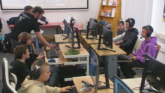 Mehrere Kinder haben Kopfhörer auf und sitzen an Computern in der Computerspielschule Greifswald. © Screenshot 