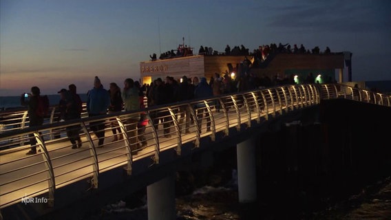 Besucherinnen und Besucher in der Dämmerung auf der neuen Seebrücke in Prerow. © Screenshot 