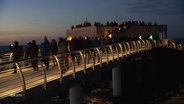 Besucherinnen und Besucher in der Dämmerung auf der neuen Seebrücke in Prerow. © Screenshot 