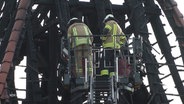 Zwei Feuerwehrmänner in einem Steigerkorb der Feuerwehr vor dem verkohlten und abgrebrannten Kirchturm der Dionysiuskirche in Bremerhaven. © Screenshot 