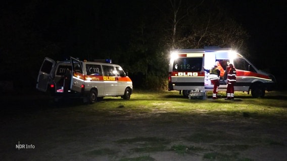 Zwei Fahrzeuge der DLRG parken auf einer Wiese, es ist Dunkel. © Screenshot 