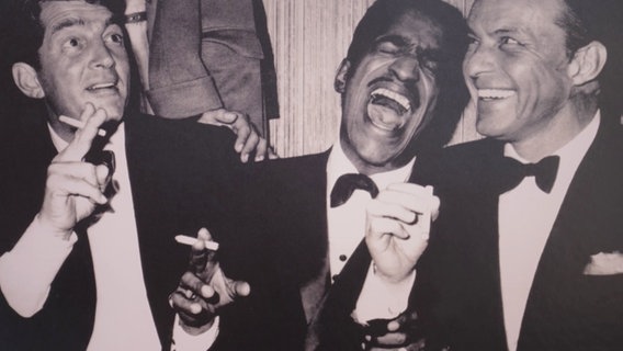 Ein berühmtes Foto zeigt Dean Martin, Sammy Davis Jr. und Frank Sinatra rauchend und lachend. © Screenshot 