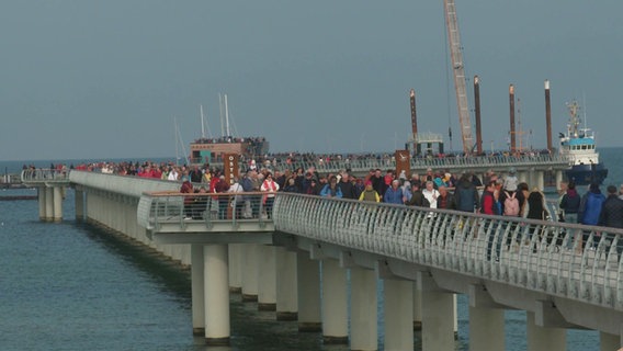 Touristen laufen über die neue Seebrücke in Prerow. © Screenshot 