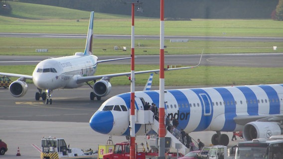 Zwei Flugzeuge stehen auf der Landebahn am Hamburger Flughafen. © Screenshot 