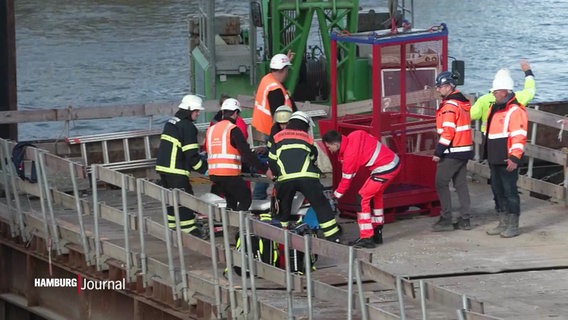 Mehrere Männer stehen auf einer Baustelle um einen verletzten Mann. © Screenshot 