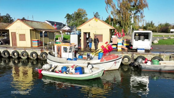 In einem kleineren Hafen liegt ein Fischerboot am Kai vor einem kleinen Hafenhäuschen. © Screenshot 