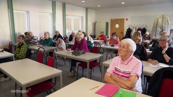 Viele Seniorinnen und Senioren sitzen in einem Klassenzimmer bei einer Vorlesung. © Screenshot 