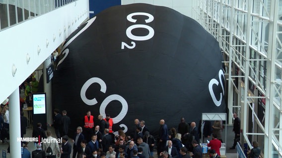 Eine große, schwarze, aufblasbare Kugel mit dem weißen Aufdruck "CO2" blockiert Eingänge in die Messehallen. © Screenshot 