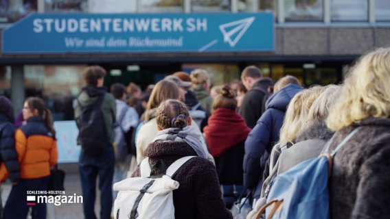 Studierende von hinten, im Hintergrund das blau-weiße Banner des "Studentenwerk SH". © Screenshot 