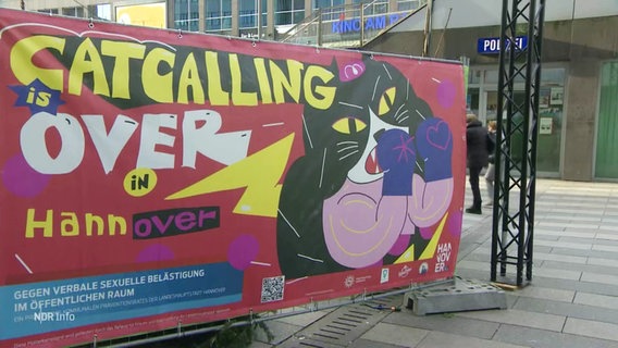 Ein Banner mit einer Katze mit Boxhandschuhen, daneben der Slogan "Catcalling is over in Hannover". © Screenshot 