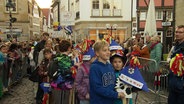 Kinder mit Steckenpferden und bunten Papiermützen ziehen durch die Stadt. © Screenshot 