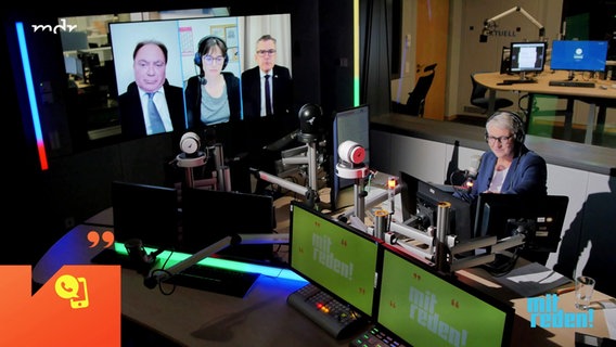 Moderatorin Doreen Jonas spricht im Studio in ein Mikrofon. Auf einem großen Bildschirm sind Dr. Hans-Walter Borries, Christina Nagel und Roderich Kiesewetter in einer Videokonferenz zugeschaltet. © Screenshot 