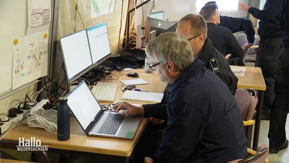 Einsatzkoordinatoren sitzen in einem Planungszelt vor Laptops bei einer Katastrophenschutzübung. © Screenshot 