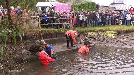 Viele Menschen schauen zu, während Fischnetze aus einem See gezogen werden. © Screenshot 