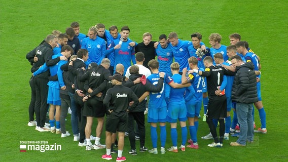 Das Team von Holstein Kiel hat sich auf dem Stadionrasen zur Besprechung versammelt © Screenshot 