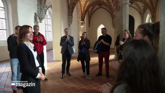 Im Lübecker Burgkloster applaudieren Menschen bei einer Führung einer Frau © Screenshot 