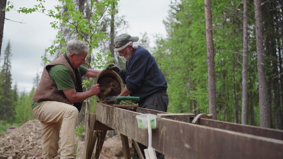 Zwei Männer schürfen in einem Wald nach Gold. © Screenshot 