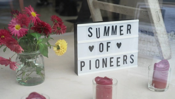 In einem Schaufenster steht ein Schild: "Summer of Pioneers". © Screenshot 