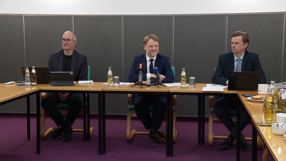 Drei Männer stellen Ergebnisse auf einer Pressekonferenz vor. © Screenshot 