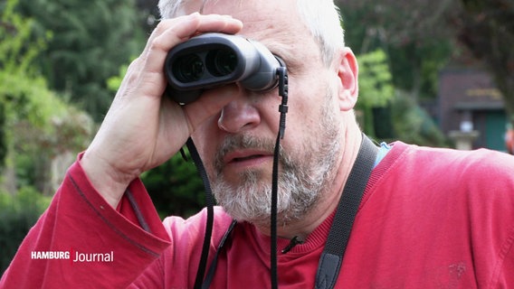 Ein Mann hält sich ein Fernglas vor die Augen. © Screenshot 