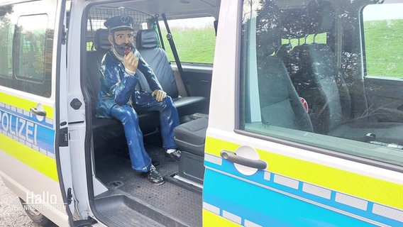 Die gestohlene Kapitänsstatue sitzt auf der Bank eines Polizeiwagens. © Screenshot 